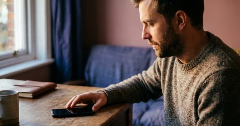 Mann sieht auf ein Smartphone, ohne es aufzunehmen