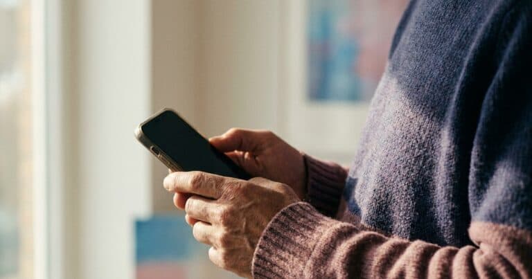 Hände halten ein Smartphone schützend nah am Körper