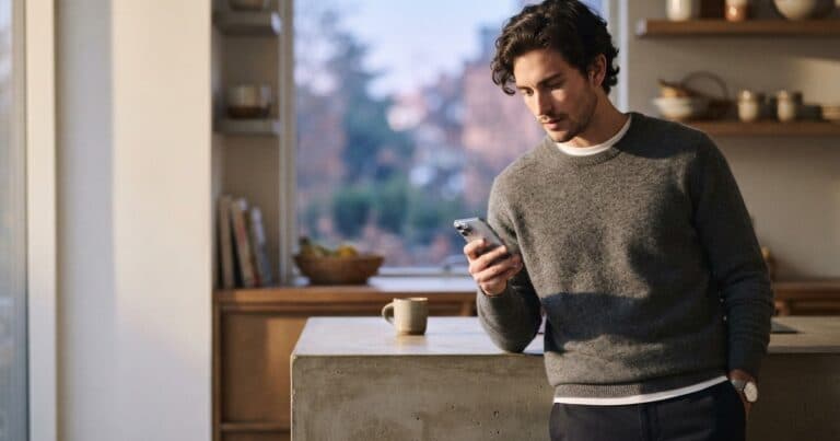 Man in a kitchen pausing with his thumb over an Instagram poll before tapping