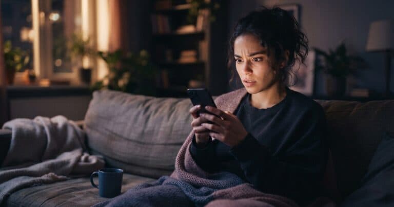 Woman on a sofa at night checking her Instagram story viewer list, unsure what the order means