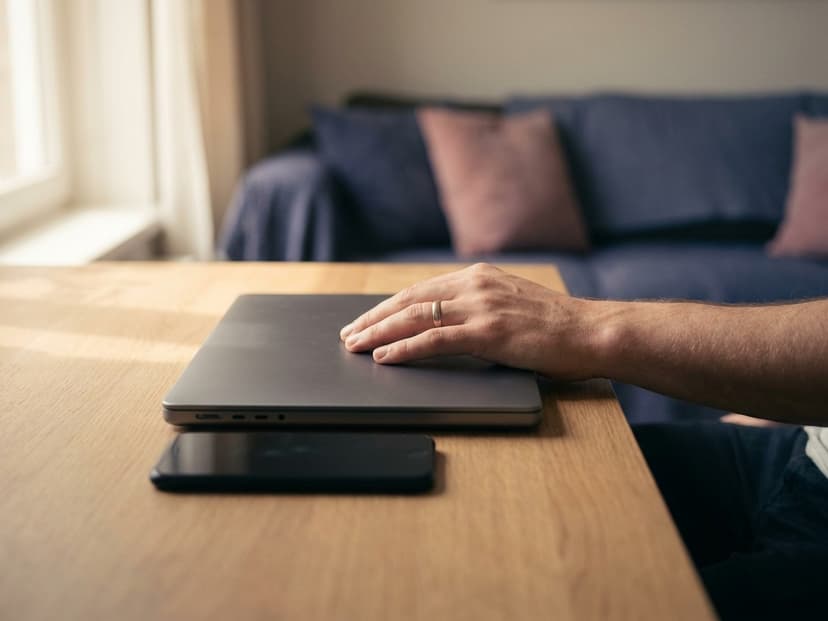Hand auf einem geschlossenen Laptop neben einem Smartphone